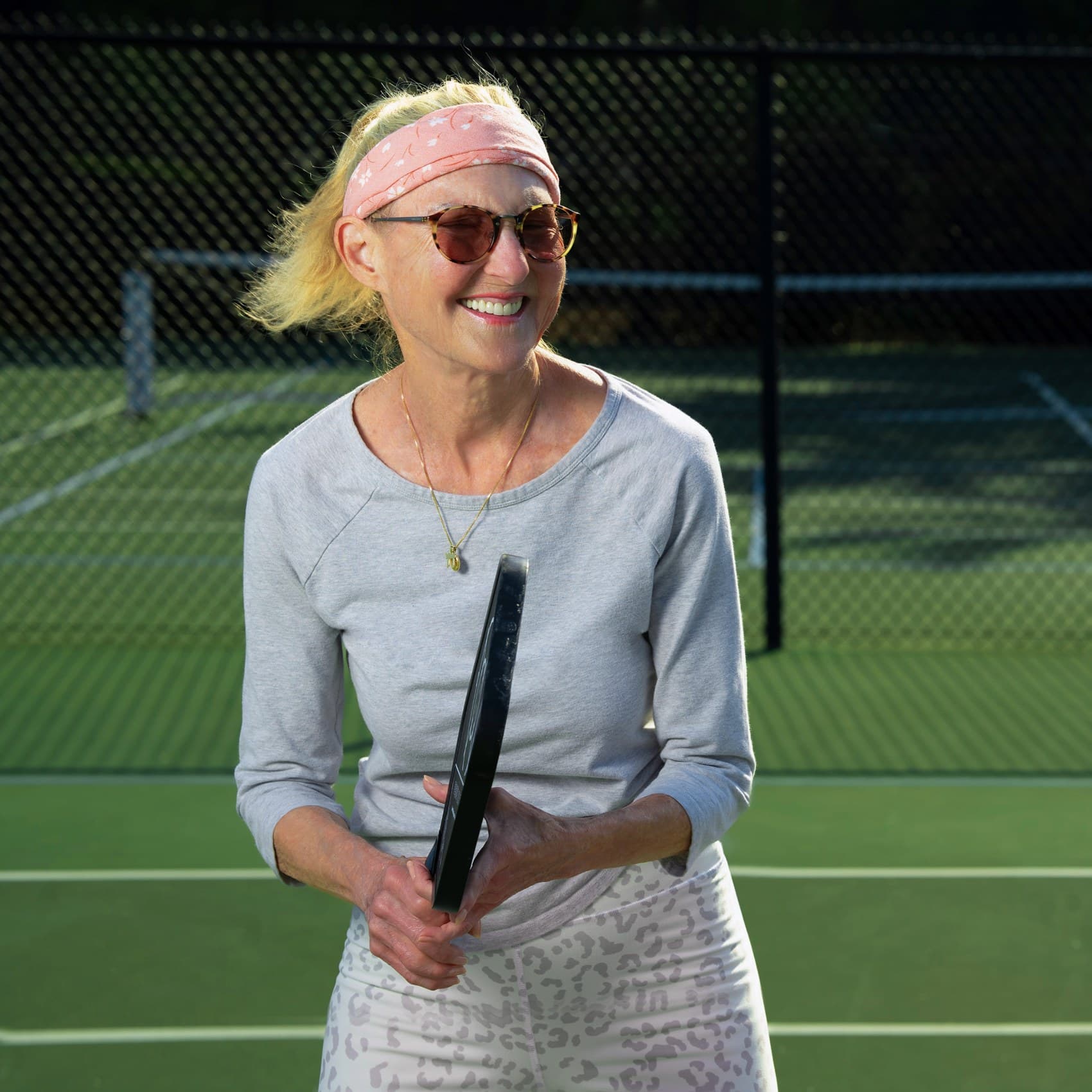 Woman smiling and playing tennis.